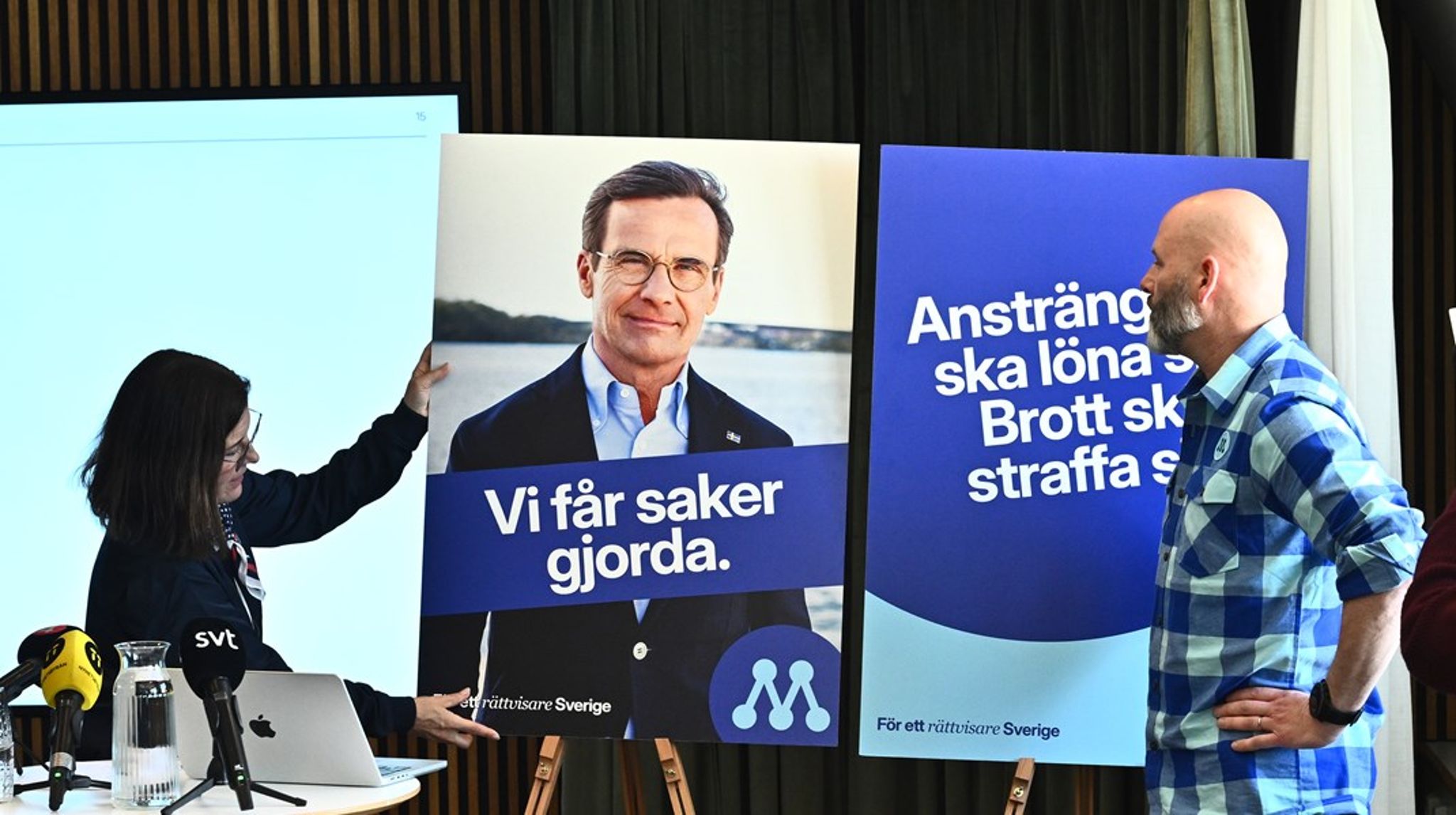Partisekreteraren Karin Enström och valgeneralen Martin Borgs visar upp valaffischerna för den politiska reporterskaran som fått en paus från bevakningen av&nbsp;kvittningskaoset.