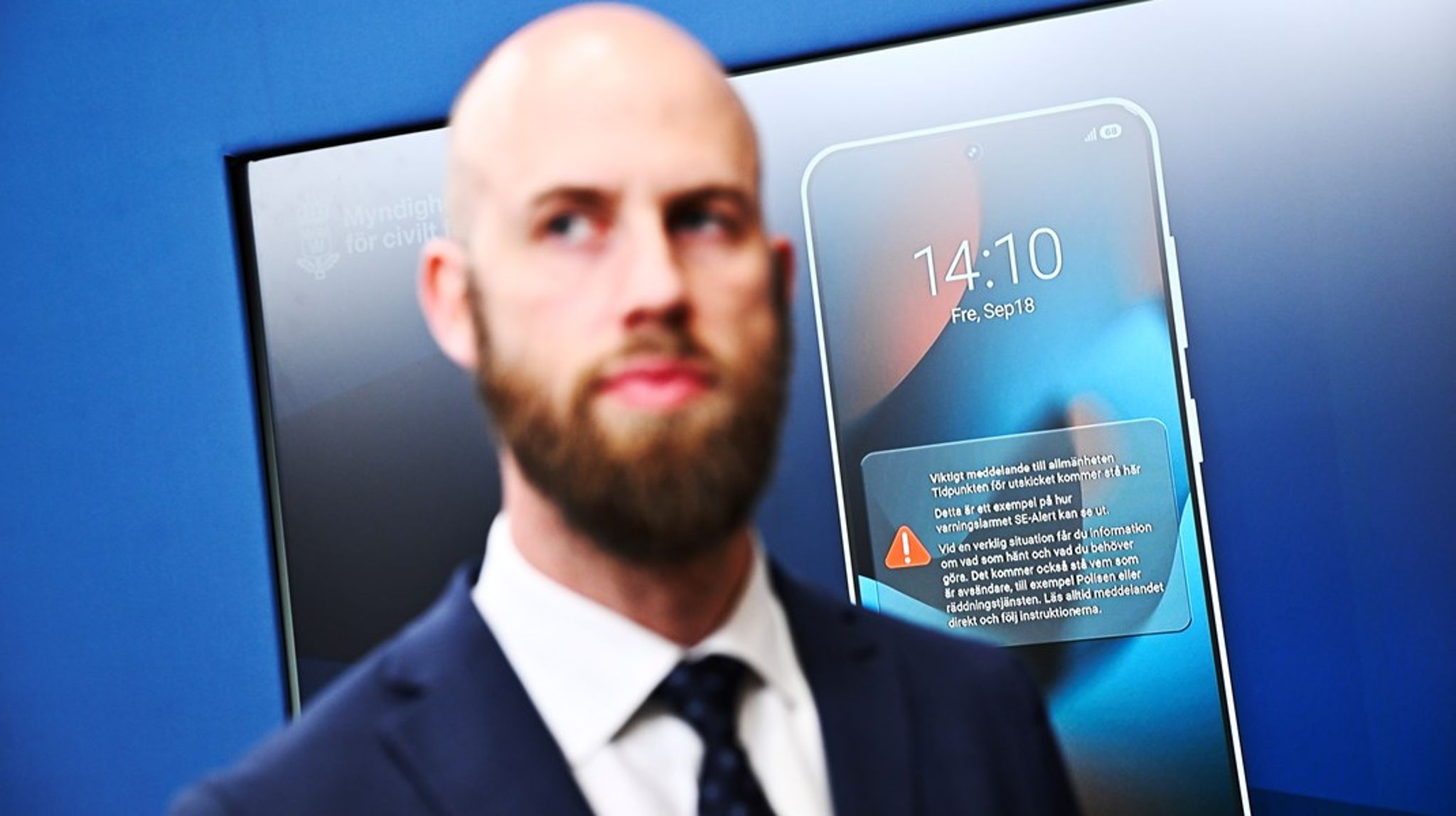 Carl-Oskar Bohlin (M) visar vid en pressträff hur varningen i mobilen kommer att se ut. 