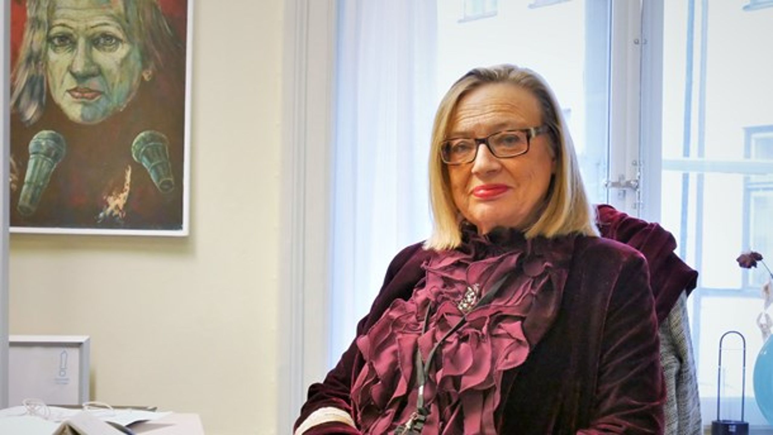 Karin Rågsjö (V) på sitt kontor. Porträttet av henne på väggen har hennes man målat.