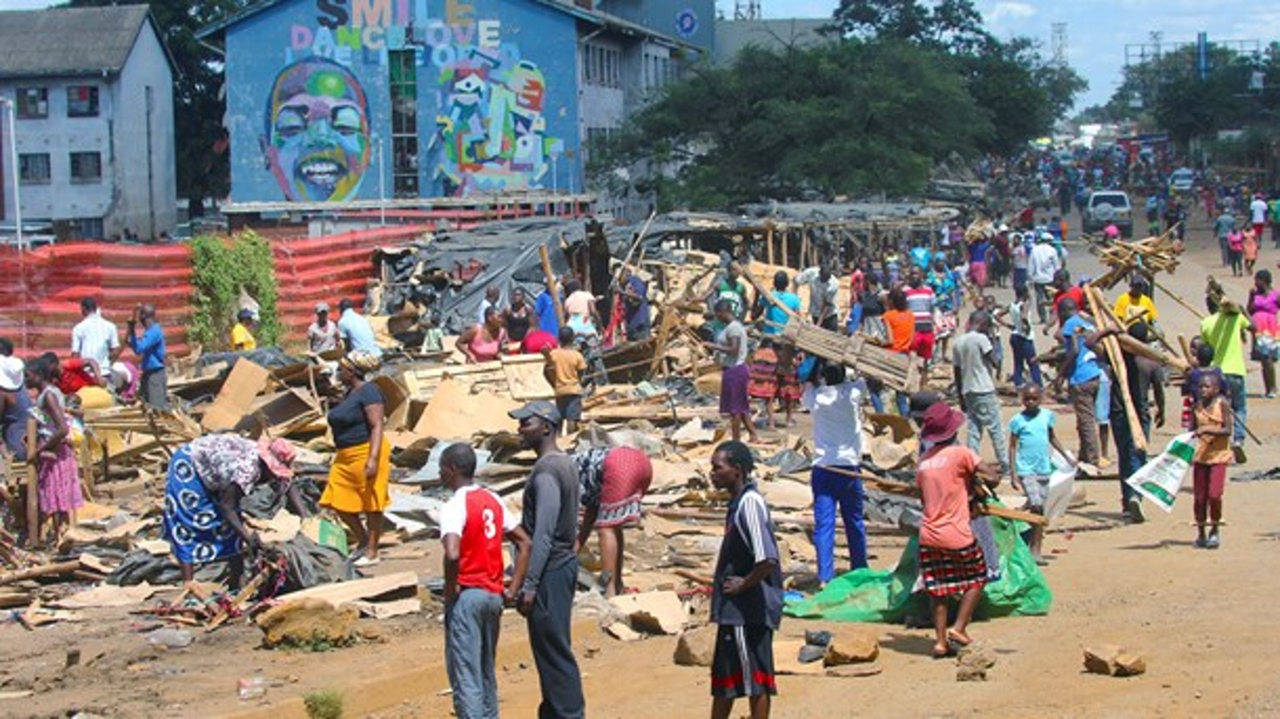 Människor i&nbsp;Harare, Zimbabwe städar bland förstörda marknadsstånd, 18 april 2020.